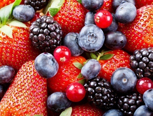 A imagem mostra morangos, amoras, mirtilos e oxicocos misturados. São frutas vermelhas consideradas alimentos ricos em colágeno.