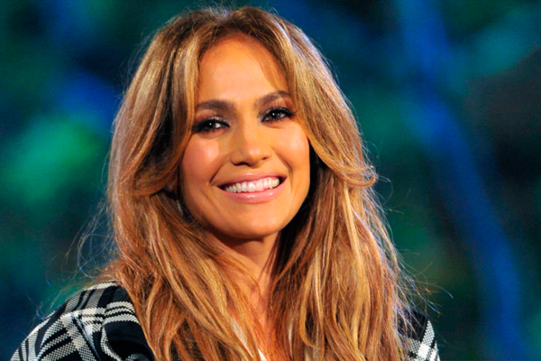 A atriz e cantora Jennifer Lopez , fotografada de perto, sorri para a câmera. Por seus cuidados com a pele, virou um dos nossos exemplos de truques de beleza das celebridades.